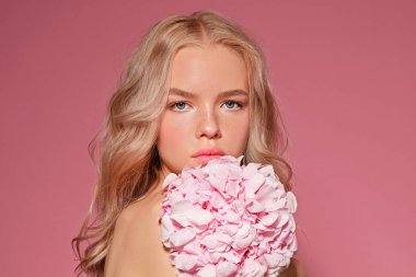 güzel sarışın model çıplak makyaj ve çiçeklerle pembe arka plan üzerinde yakın çekim