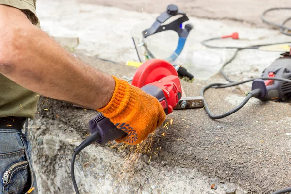 The worker uses an angle drive grinder to work with a metal corner. Angle drive grinder in action.