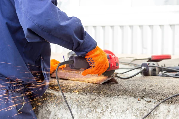 The worker uses an angle drive grinder to work with a metal corner. Angle drive grinder in action.