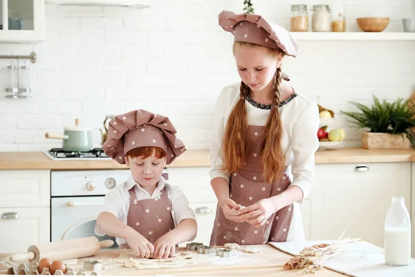 Cooking with kids. Happy funny children preparing the dough, bake cookies in the kitchen. Chef kids having fun in the kitchen. Warm sunny day.