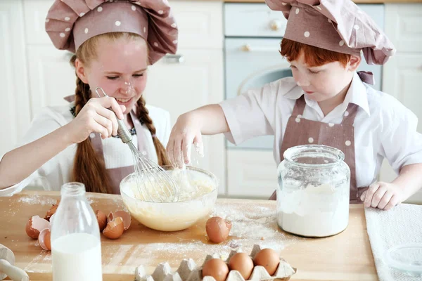 Cooking with kids. Happy funny children preparing the dough, bake cookies in the kitchen. Chef kids having fun in the kitchen. Warm sunny day.