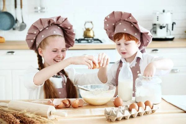 Cooking with kids. Happy funny children preparing the dough, bake cookies in the kitchen. Chef kids having fun in the kitchen. Warm sunny day.