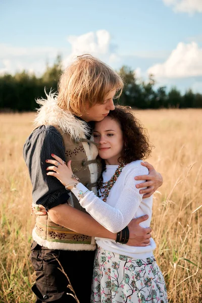 Boho style attractive couple in love posing on the autumn field. Family having fun and laughing. Gypsy style clothes. Young blonde man and beautiful caucasian woman together outdoor.