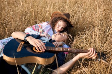 Üstten görünüm birkaç içinde aşkın bir sonbahar çim üzerinde yalan. Güzel genç kadın ve sarışın adam eğleniyor gitar ile gülümseyen. Çift ilişkiler. Yumuşak güneşli renkleri.