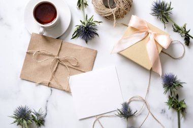Kahve, mavi çiçekler, kartpostal, kraft zarf, sicim, pamuk şube, Hediyelik, Davetiyeli kopya alanı metin için fincan ile mermer masası. Düz yatıyordu, en iyi görünüm. Kadının gün veya annenin gün mockup.