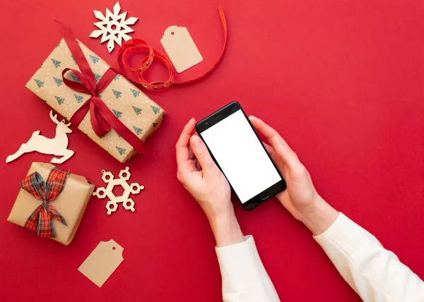 Mãos Femininas Segurando Telefone Fundo Vermelho Com Decorações Natal Presentes — Fotografia de Stock