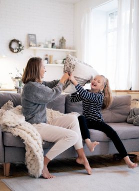 Anne ve çocuk eğleniyor yastık yatak odasında çekyat üzerinde mücadele. Mutlu aile evde birlikte vakit.