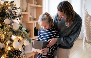 Anne kızı Noel hediyesi mevcut. Sunny Noel sabahı, doğal yumuşak renkler.