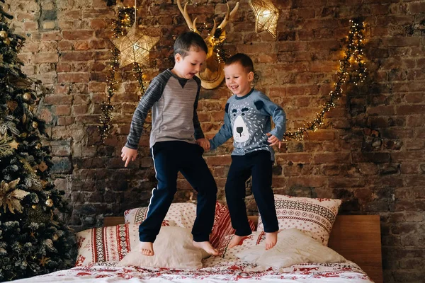 Happy kids jumping on bed. Brothers having fun on bedroom at Christmas morning
