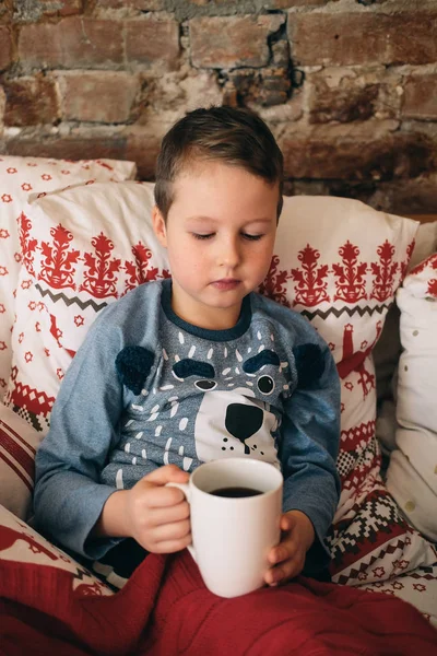 Genç yakışıklı bir battaniye ile yatakta sıcak çikolata sahip