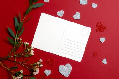 Sevgililer günü kompozisyon: boş kartpostal, yeşil çiçekler Grup, tebrik Kalp Sevgililer kartları kırmızı zemin üzerine şeklinde. Aşk çift ilişki kavramı.