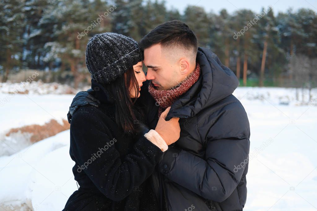 Close up portrait of young attractive couple in love embracing outdoor in winter park. Sensual tender boyfriend and girlfriend enjoying romantic moment together, feeling intimacy and closeness.