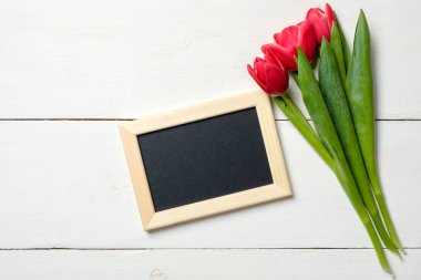 Daveti veya kırmızı lale çiçek Beyaz ahşap masa üzerinde grup ile kutlama için boş kart. Vintage afiş mockup için bahar tatil, Uluslararası Kadınlar günü 8 Mart, düğün, anneler günü