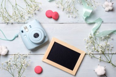 Modern polaroid fotoğraf makinesi, acıbadem kurabiyesi kurabiye, fotoğraf çerçevesi, rustik ahşap arka plan mavi çiçekler. Üstten Görünüm, ihale en az düz stil kompozisyon yatıyordu. Kadın Danışma, moda blogger, güzellik teknoloji