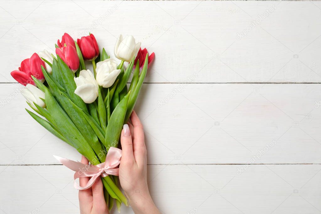 Womans hands holding Bouquet of tulips on white wooden horizontal striped board. Greeting card for International Womans Day, Mothers Day, wedding, birthday, spring holidays. Vintage mockup, copy space