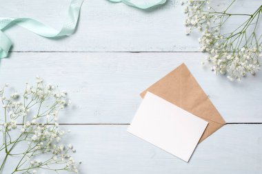 Kraft zarf ve çiçekli mavi ahşap masa boş kartı. Senin kutlama Paskalya, anne veya kadının gün, Bahar arka plan boş tebrik kartı,