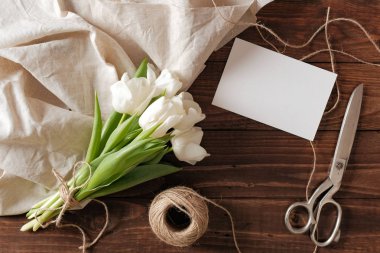 Boş düğün davetiye kartı ve ahşap masaya bahar çiçek salkımı. Beyaz Lale, tekstil bez, sicim, romantik düğün tebrik kartı.