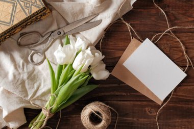 Beyaz Lale çiçek, boş kağıt kartı, makas buket Bahar, rustik ahşap masanın üstünde sicim. Kadın gün Bileşim görünümünün üzerinde düz yatıyordu stili.
