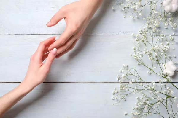 Young couple hand on blue wooden table with flowers . Bonding concept, flat lay, above view