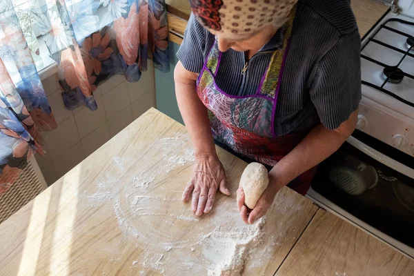 Grandmother cooking in the kitchen, kneading dough for bakery