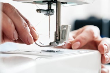İş parçacığı tutarak ve bir dikiş makinesi iğne threading kadın eli