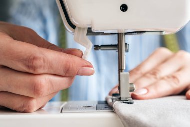 Elinde bir dikiş makinesi kullanan bir kadın terzi Atölyesi.