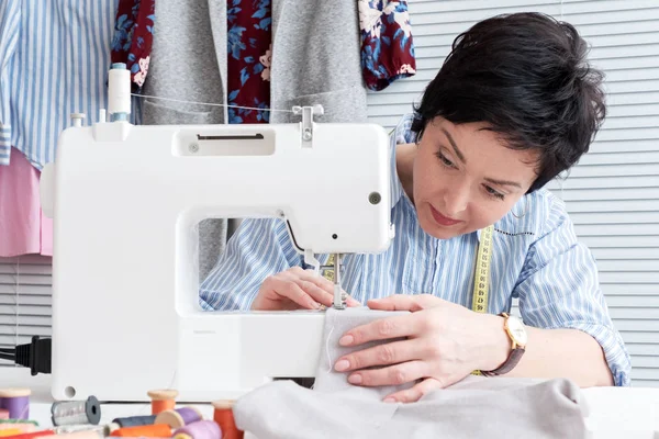 Seamstress working at tailor shop with electrical industrial sewing machine