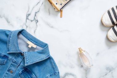 Resepsiyon güzellik Blogger kadınsı Kot ceket, kozmetik çantası, parfüm şişe parfüm ile şık sandalet çizgili. Retro moda Bayan giyim ve aksesuarları mermer zemin üzerine.
