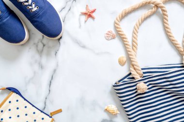 Yaz tatil kompozisyon. Moda mavi spor ayakkabı, çizgili plaj çantası, deniz kabuklarını, deniz yıldızı mermer zemin üzerine. Gezgin, güzellik blogger, dijital göçebe, hippi kız ve kadın Danışma