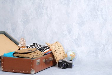 Gri arka plan, seyahat giyim, aksesuar ile açılan dava üzerinde tam seyahat bavul. Afiş mockup kopya alanı ile. Seyahat ya da turizm, tatil, tatil kavramı