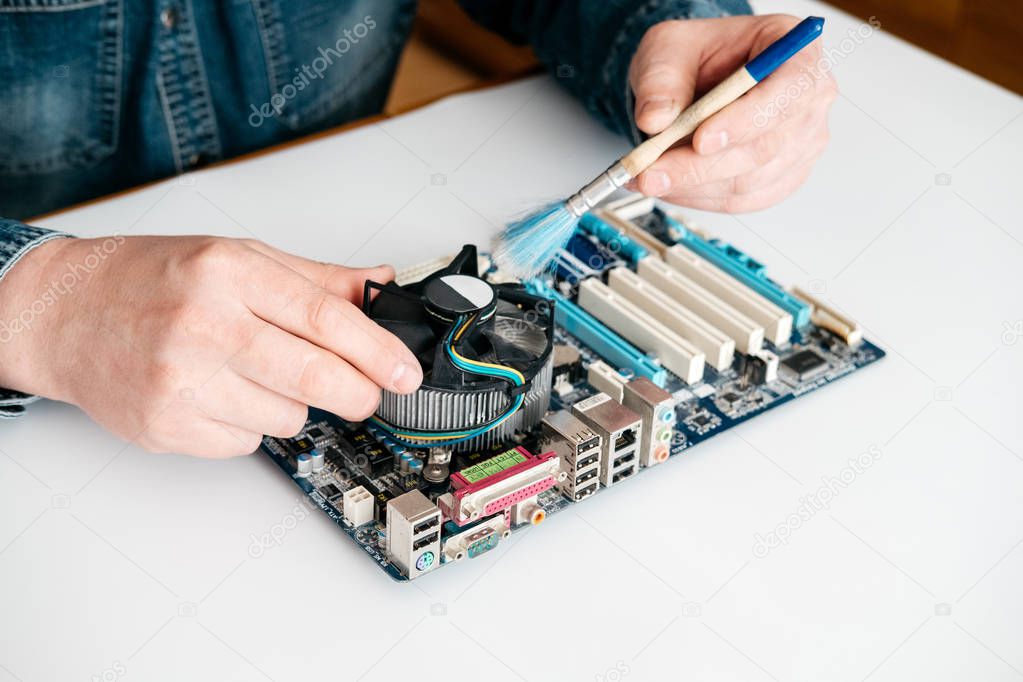 Technician using brush for computer cleaning, clean the motherboard from dust