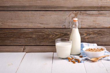 Badem veya soya sütü şişe ve cam, badem ile kase rustik ahşap arka planda dağılmış. Sığır sütü alternatifleri konsepti