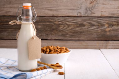Rustik ahşap masada etiket ve badem fındık ile şişe badem sütü. Laktoz ücretsiz süt ürünleri kavramı