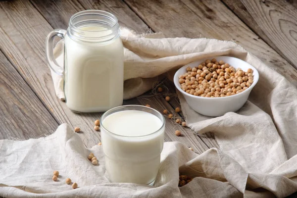 Vaso y frasco de sabrosa leche de soja en la mesa de madera, directamente encima, concepto de leche orgánica vegana, sin lactosa, sin gluten, sustituto de leche sin diario natural . — Foto de Stock