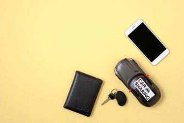 Carsharing kavramı. Oyuncak araba, Araba anahtarı, sarı arka planda akıllı telefon ve sürücü lisansı. Minimal düz stil kompozisyon, üst görünüm, kopya alanı yatıyordu. Araç Kiralama ajansı için banner mockup