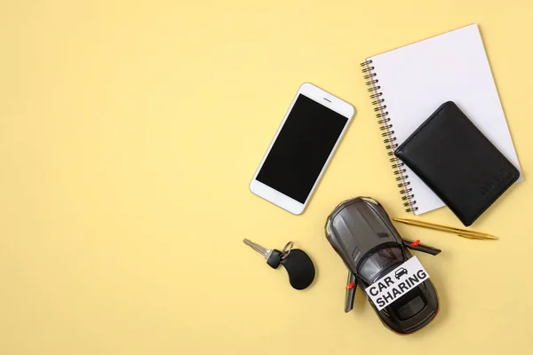 Car sharing service concept. Mobile phone with black screen, car model, automobile key, driver license, notepad, text sign "CAR SHARING" on yellow background. Carsharing mobile app. — Stock Photo, Image