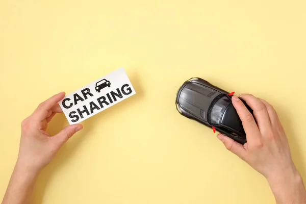 Car sharing concept. Human hands holding toy car model and text sign \