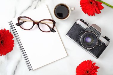 Düz yatıyordu kadın ev ofis masası. Kağıt not defteri, retro fotoğraf makinesi, kahve fincanı, kadınsı gözlük ve mermer arka plan üzerinde papatya çiçekleri ile çalışma alanı. Moda blog afiş, güzellik blogger işyeri