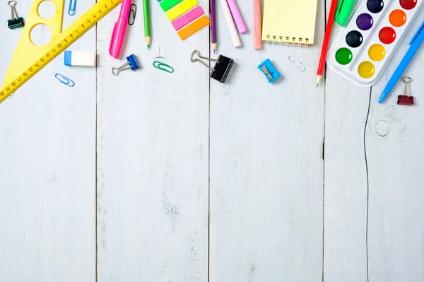 Artículos escolares papelería, lápices de color, pinturas, papel sobre tabla de madera azul pastel, volver al concepto de fondo de la escuela con espacio de copia gratuita para el texto, la educación primaria moderna. Escritorio para niños vista superior . — Foto de Stock