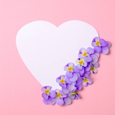 Çiçek çerçeve sınır beyaz kalp şeklinde kağıt, çiçek yaprakları, suluboya bahar arka plan üzerinde yeşil yaprakları yapılmış. Davet, tebrik kartı veya tasarımınız için bir öğe. Üst görünüm, soyut sanat.