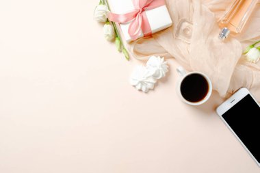 Düz yatıyordu ev ofis masası. Kahve fincanı, cep telefonu, marshmallow, hediye kutusu ve pastel pembe arka plan üzerinde eşarp ile Kadın çalışma alanı. Üst görünüm kadınsı arka plan.