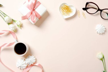 Düz yatıyordu ev ofis masası. Kurdele, kahve fincanı, hediye kutusu, marshmallow ve pembe arka plan üzerinde gül ile Kadın çalışma alanı. Metin için kopyalama alanı ile üst görünüm kadınsı arka plan.