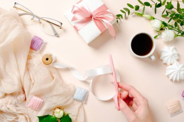 Düz yatıyordu, kahve fincanı, çiçek, marshmallow, hediye kutusu ve pembe arka plan kurdele ile makaralar ile üst görünüm kadınsı masa. Şenlikli ev ofis masası konsepti, kız aksesuarları ile kadın çalışma alanı
