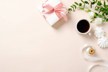 Düz yatıyordu, kahve fincanı, çiçek, marshmallow, hediye kutusu ve pembe arka plan kurdele ile makaralar ile üst görünüm kadınsı masa. Şenlikli ev ofis masası konsepti, kız aksesuarları ile kadın çalışma alanı