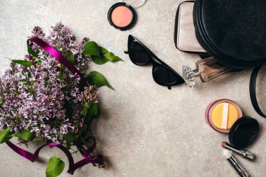 Düz bahar leylak çiçekler, güneş gözlüğü, deri çanta, cüzdan, kadın kozmetik, beton taş arka plan üzerinde parfüm ile modern minimal ev çalışma masası yatıyordu. Üst görünüm kadınsı şeyler, moda blog kahraman