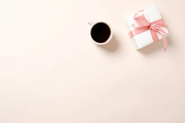 Gift box and cup of coffee on pastel pink background. Flat lay home office desk, top view feminine background. — Stock Photo, Image