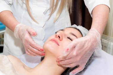 Yüz masajı. Genç güzel kadın profesyonel yüz tedavisi elde. Spa, tatil, güzellik ve sağlık konsepti