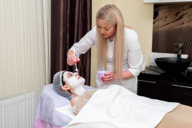 Yüz soyma maskesi, kaplıca güzellik tedavisi, cilt bakımı. Güzellik salonunda güzellik uzmanı bir kadının yüz bakımını alıyor..