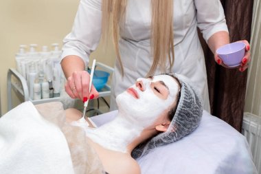 Yüz soyma maskesi, kaplıca güzellik tedavisi, cilt bakımı. Güzellik salonunda güzellik uzmanı bir kadının yüz bakımını alıyor..