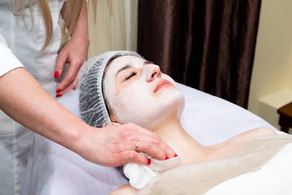 Face peeling mask, spa beauty treatment, skincare. Woman getting facial care by beautician at spa salon. Spa, resort, beauty and health concept